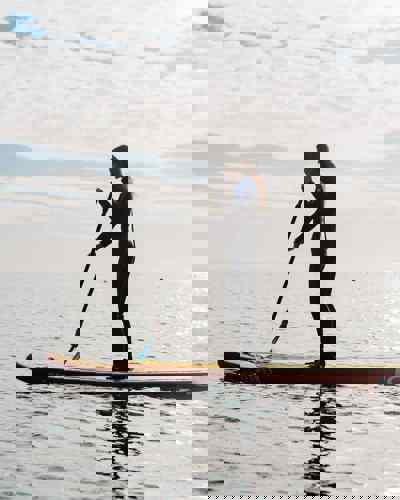 Woman paddleboarding on calm sea in Ardmore