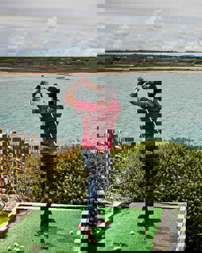 Guest practicing golf with sea view at Cliff House Hotel