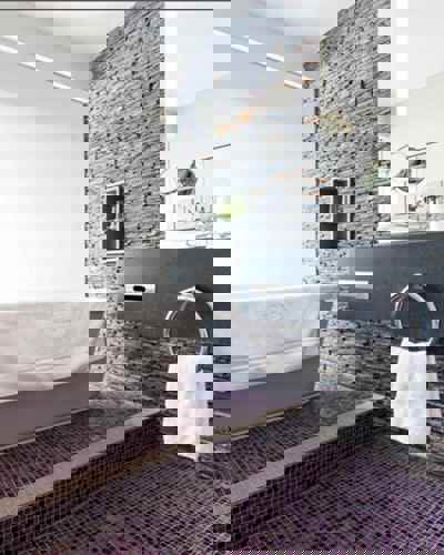 Stone-walled bathroom with freestanding bath at Cliff House Hotel