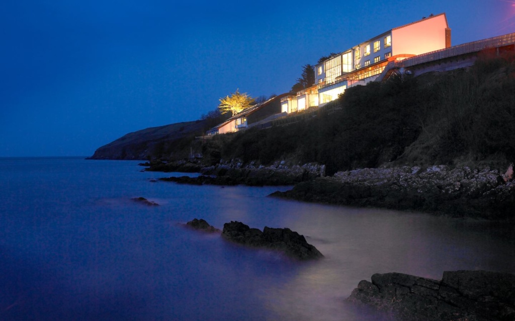The five-star Cliff House Hotel during the Christmas season, set against a deep blue evening sky and dark oceanic stretches